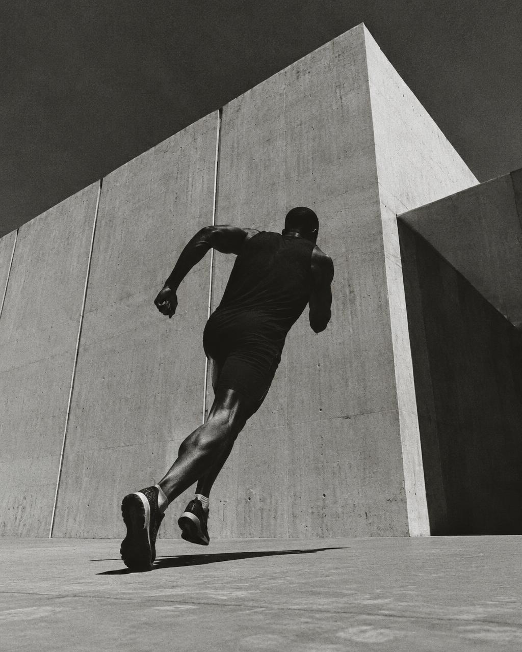 Black and white runner sprinting past a concrete wall
